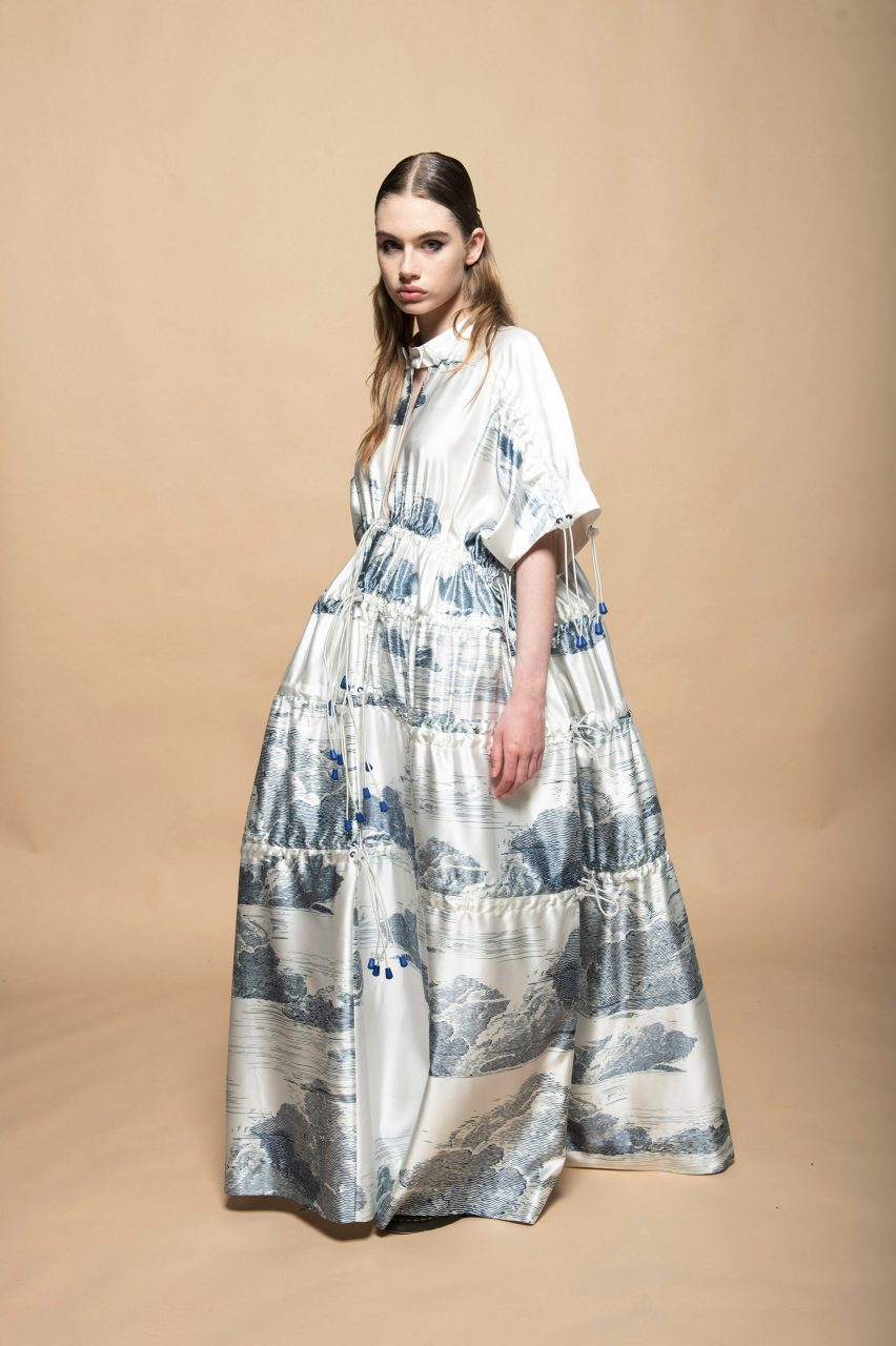 Model wearing full length white dress with blue print