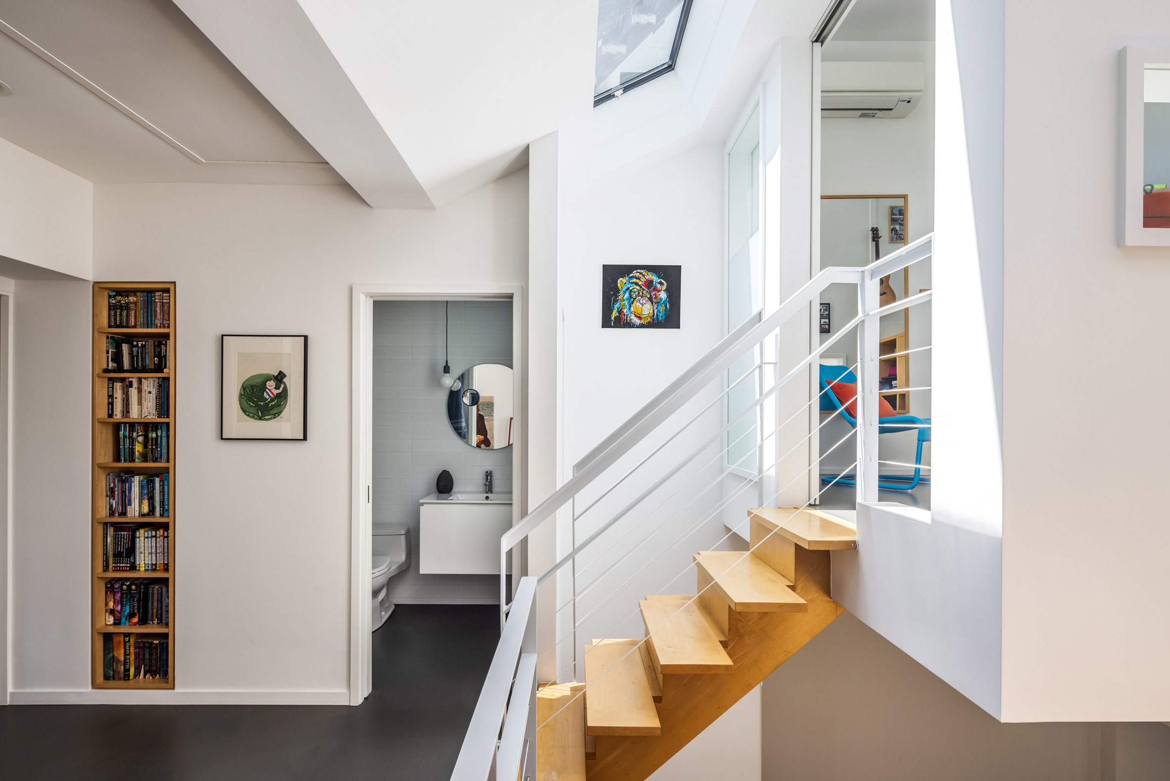 Maple staircase leading to white floating box in Brooklyn townhouse
