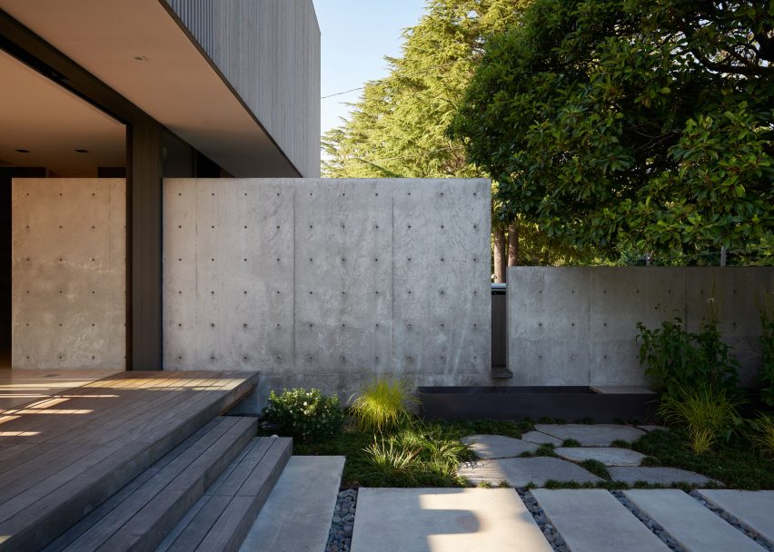 Concrete walls and garden path surrounded by trees designed by Heliotrope