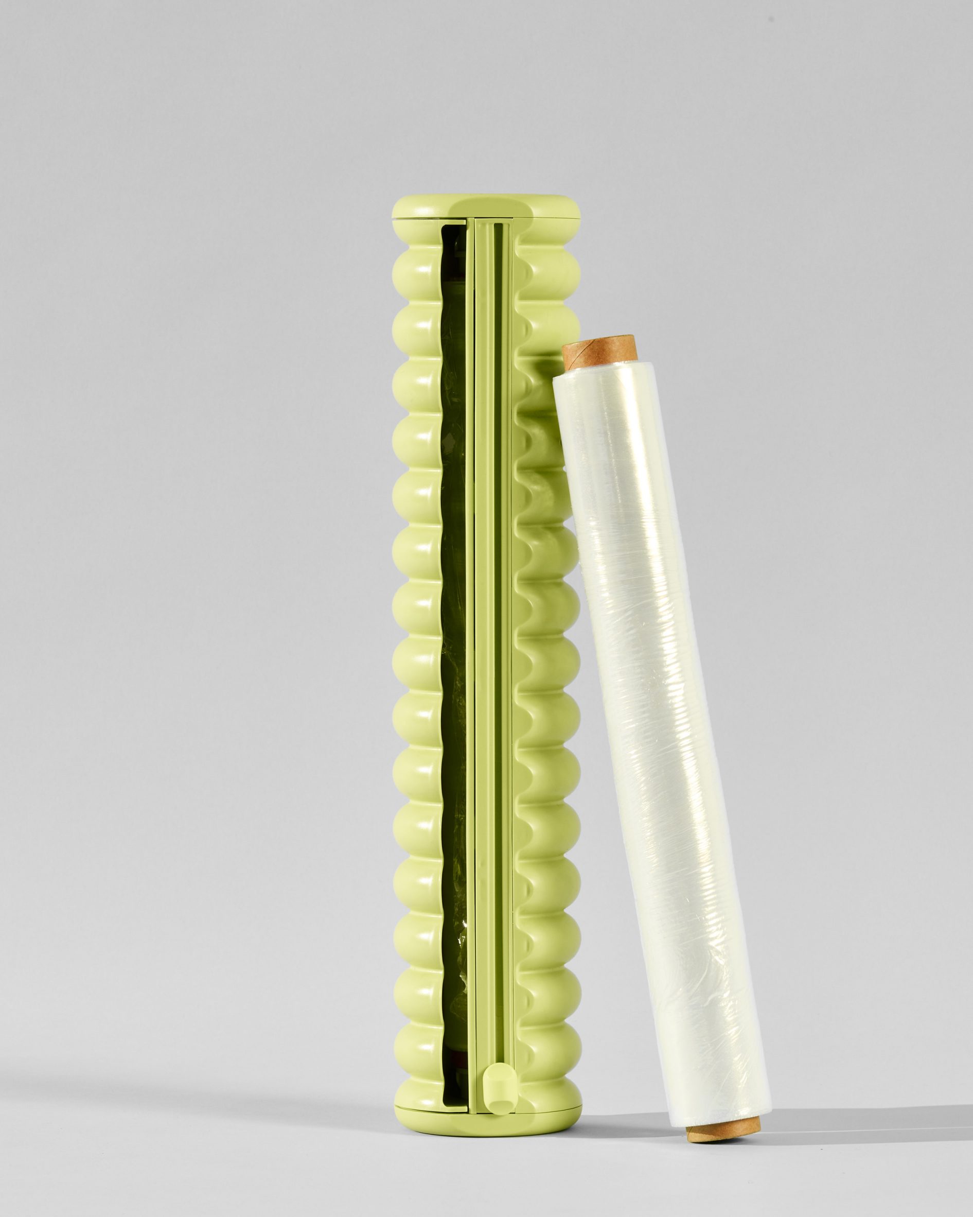 A roll of cling film next to a green dispenser