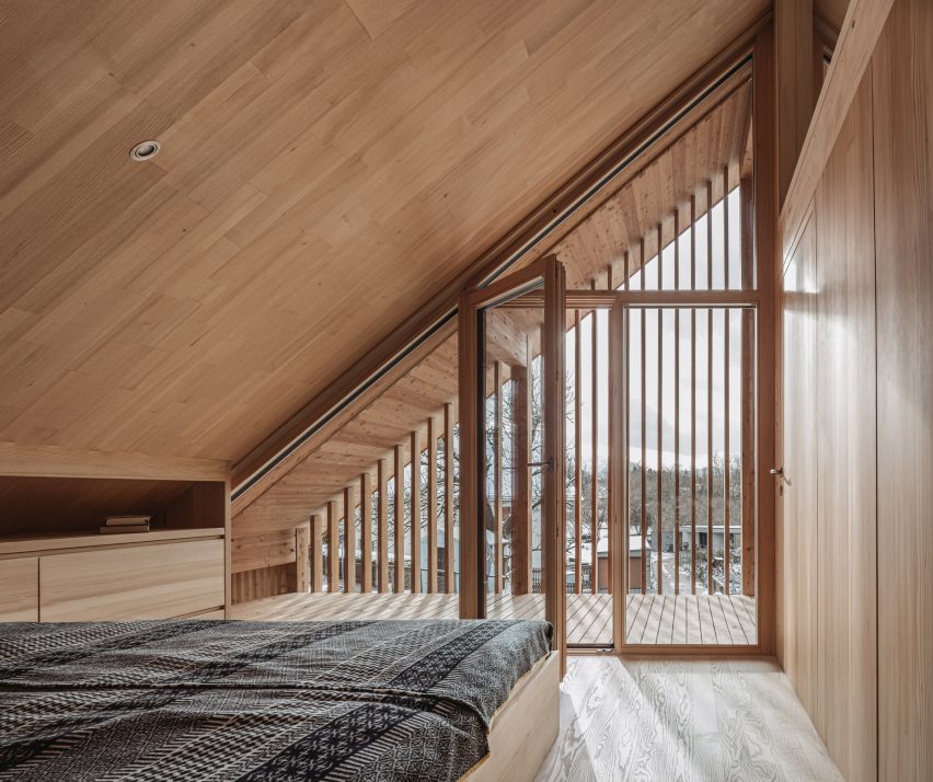 Timber slats separating balcony from bedroom with sloped ceiling in Austria alpine house