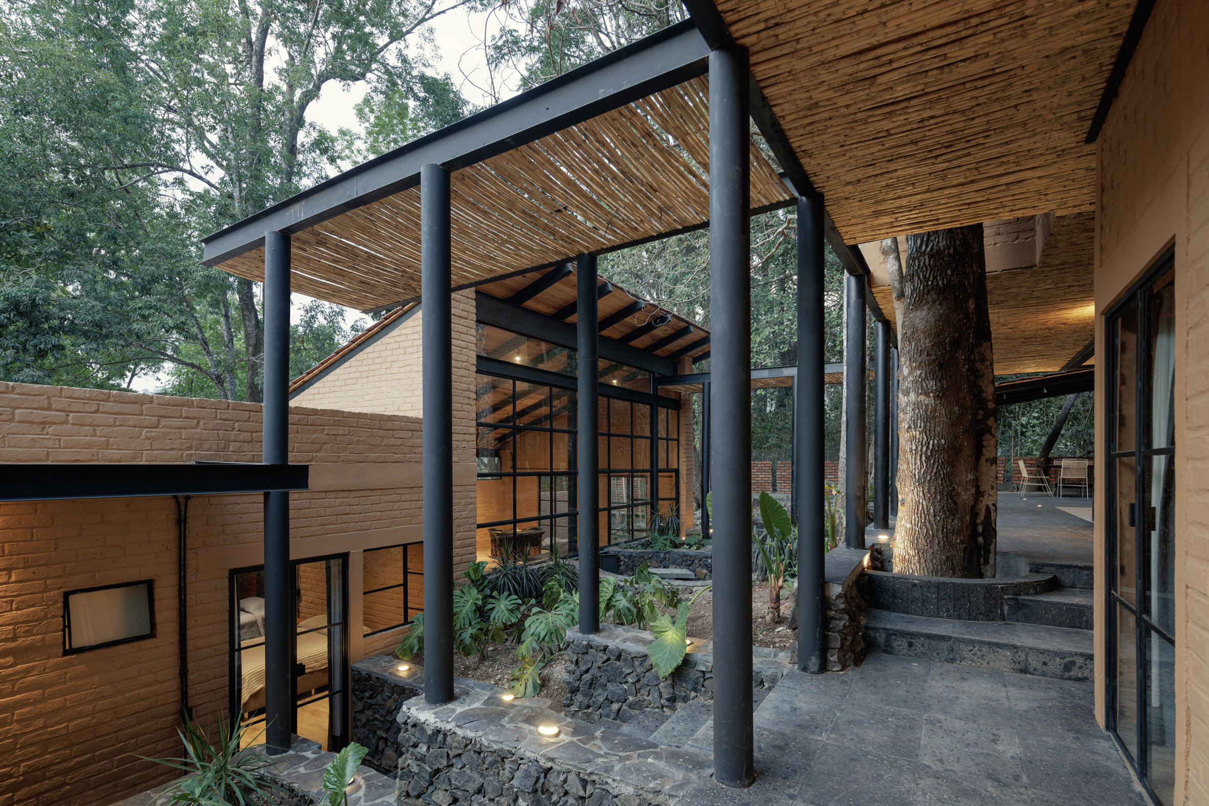Terraced courtyard in Mexico forest home supported by black poles
