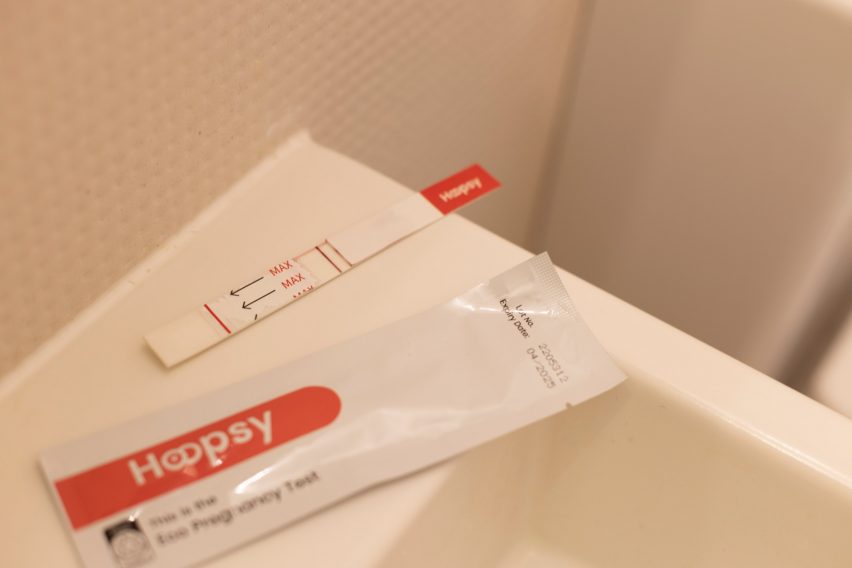 Paper pregnancy test and packaging sitting on the edge of a basin