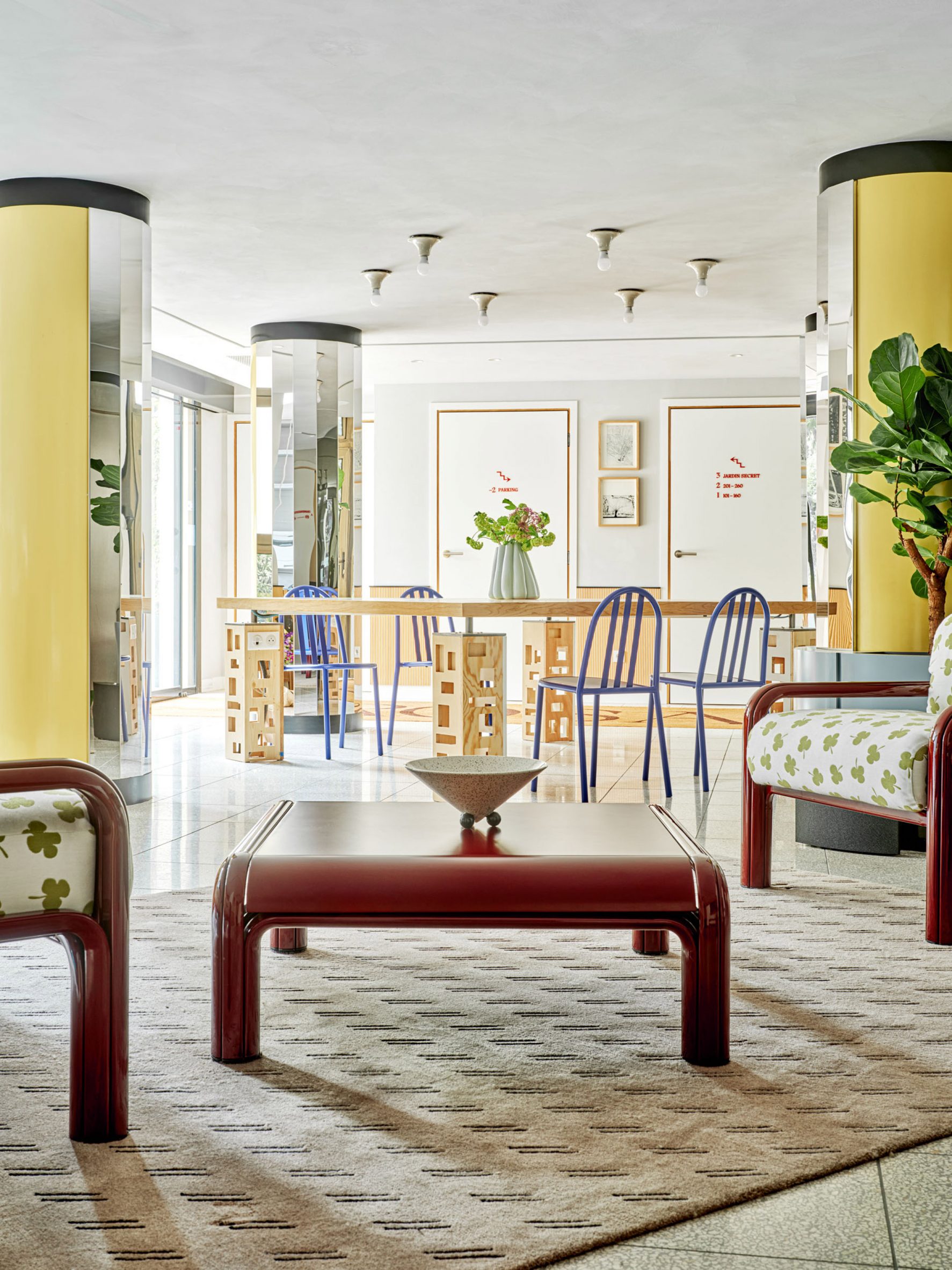 Yellow mirrored columns in hotel lobby with pre-owned chairs and plants