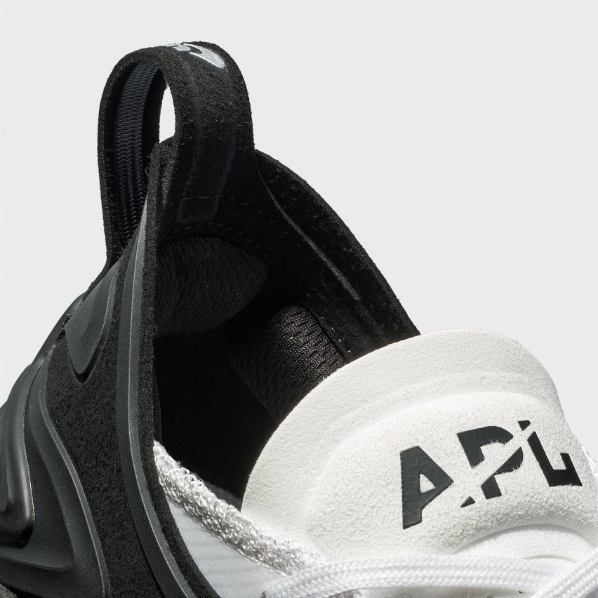 A black and white trainer with the letters APL on the tongue