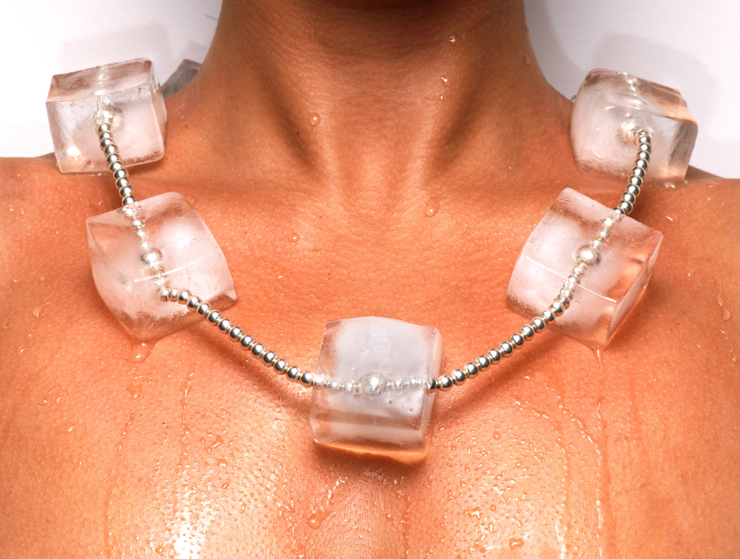Person wearing necklace made from melting ice cubes on silver chain