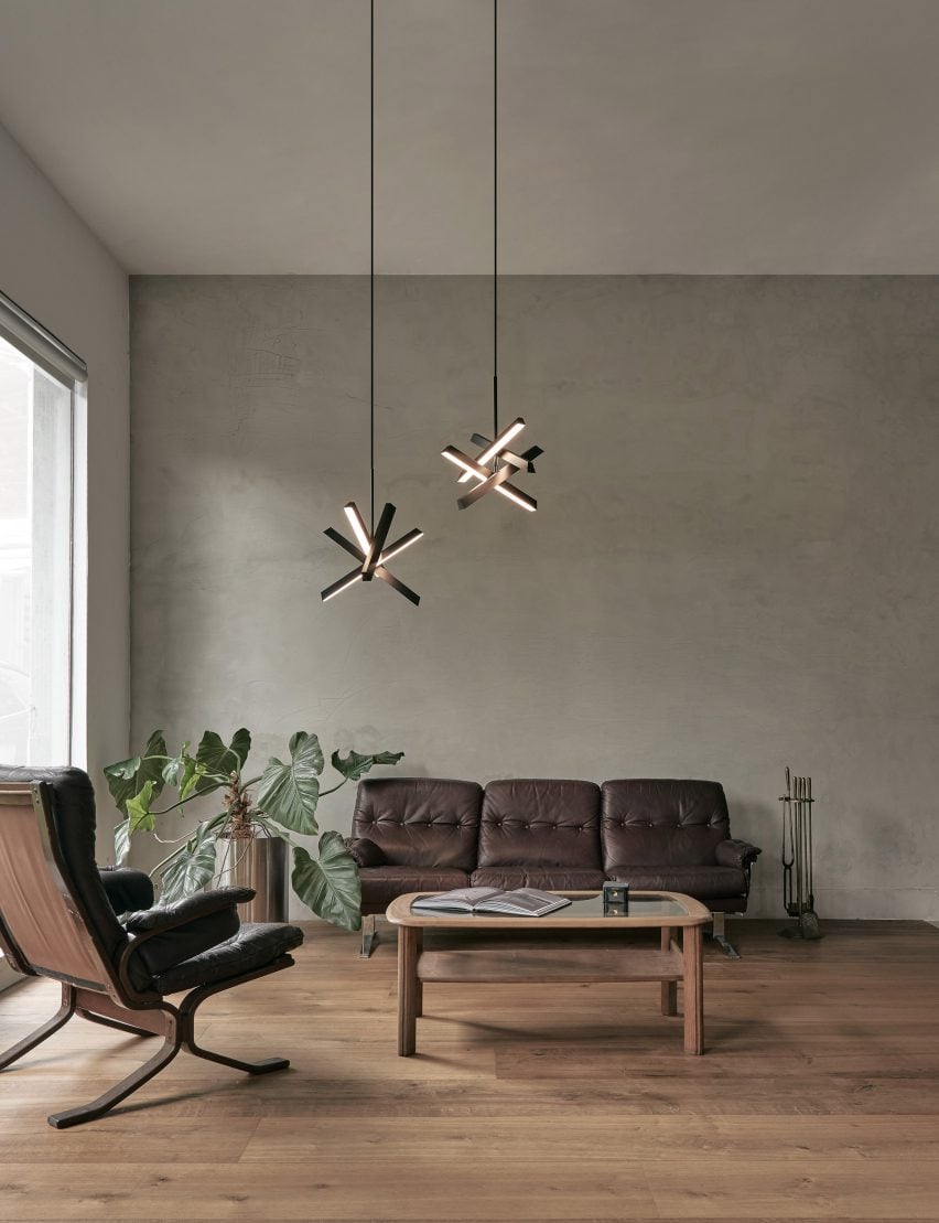 Two Konnect pendant lamps in a living room with neutral-toned walls, wooden floor and brown sofa and armchair