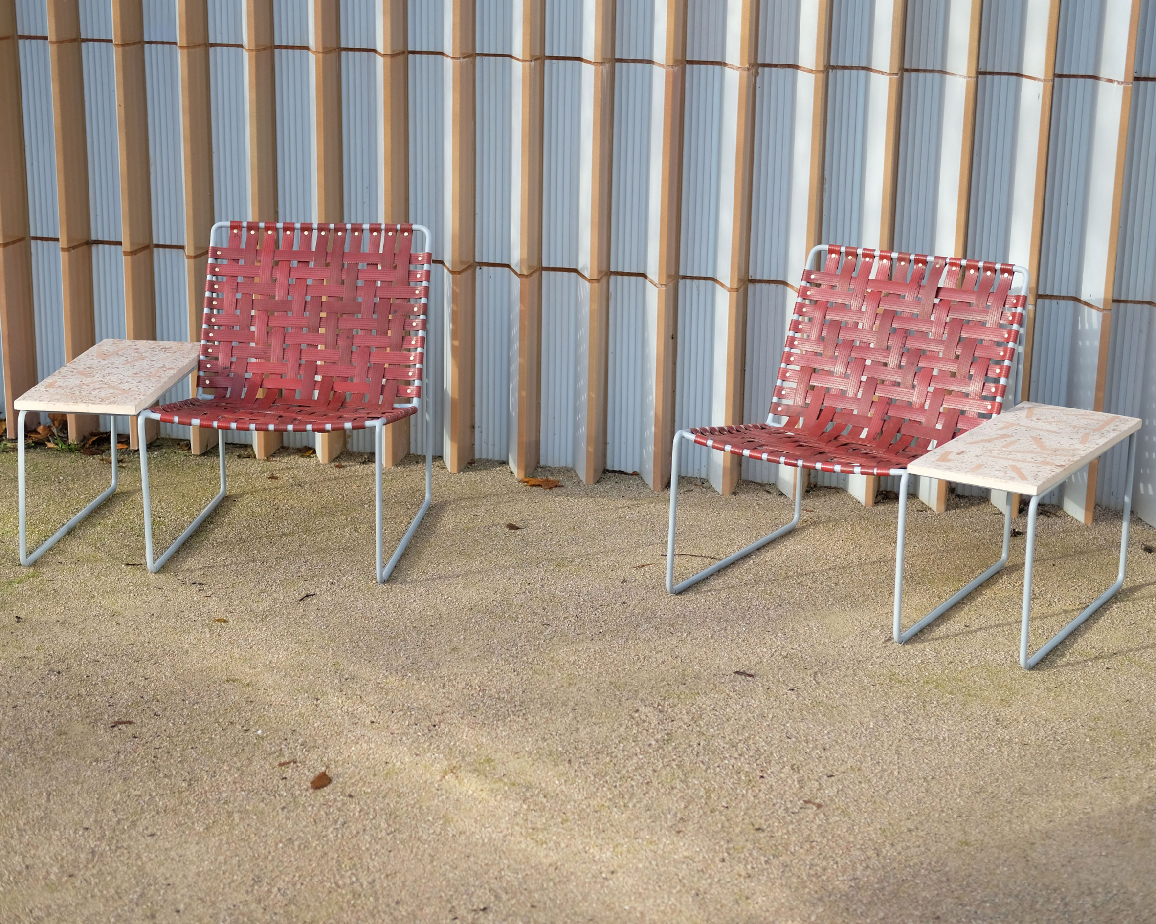 Two red lounge chairs with integrated terrazzo side tables by Local Works Studio