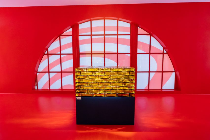 Trunk made from gold glass bricks on black platform in red room for Louis Vuitton exhibition