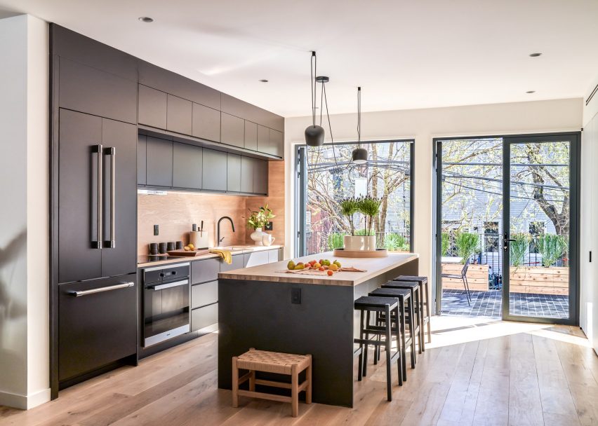 Open kitchen with black furnishings and timber accents leading to deck