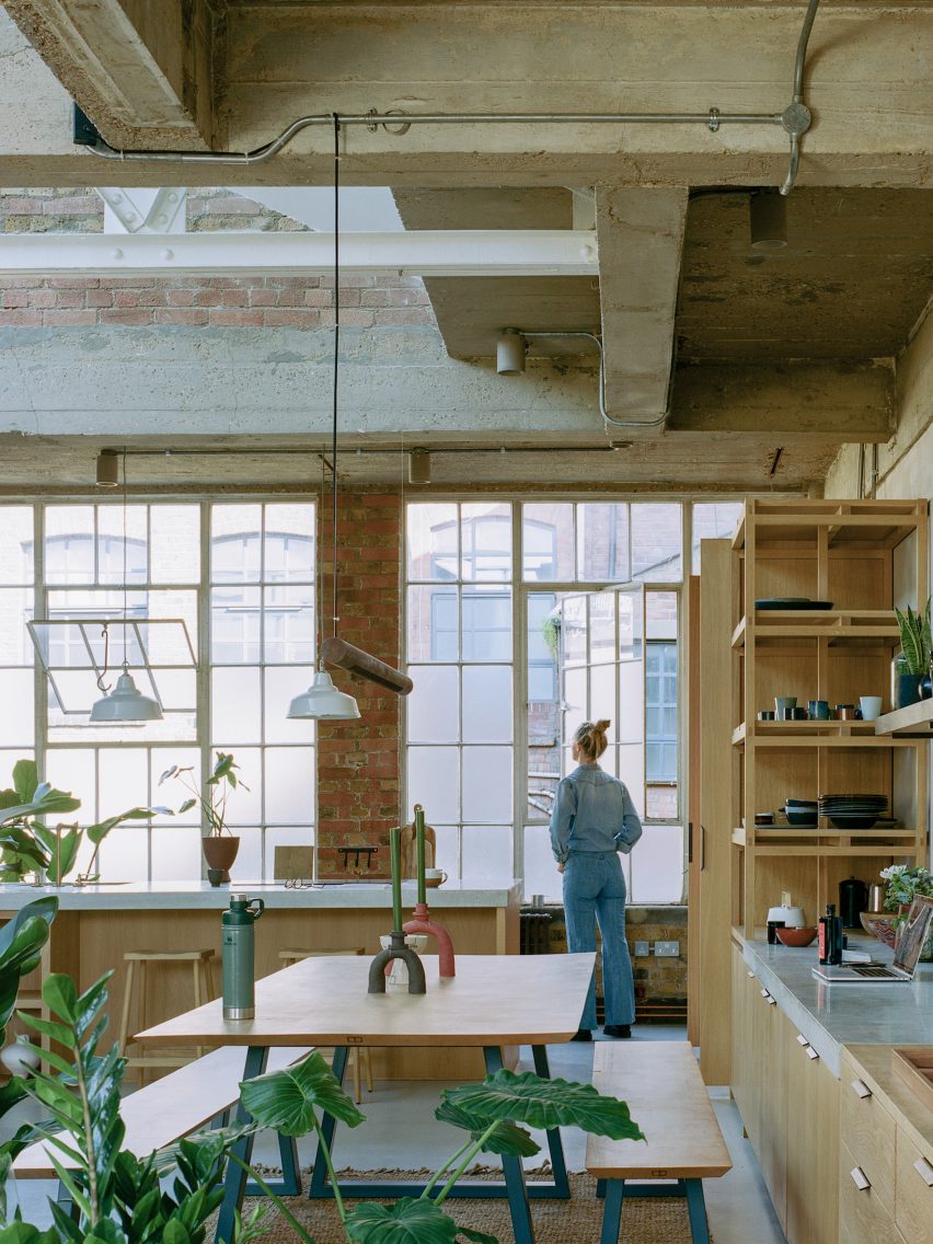 Exposed concrete walls of 20th-century warehouse with shelving units and oak table
