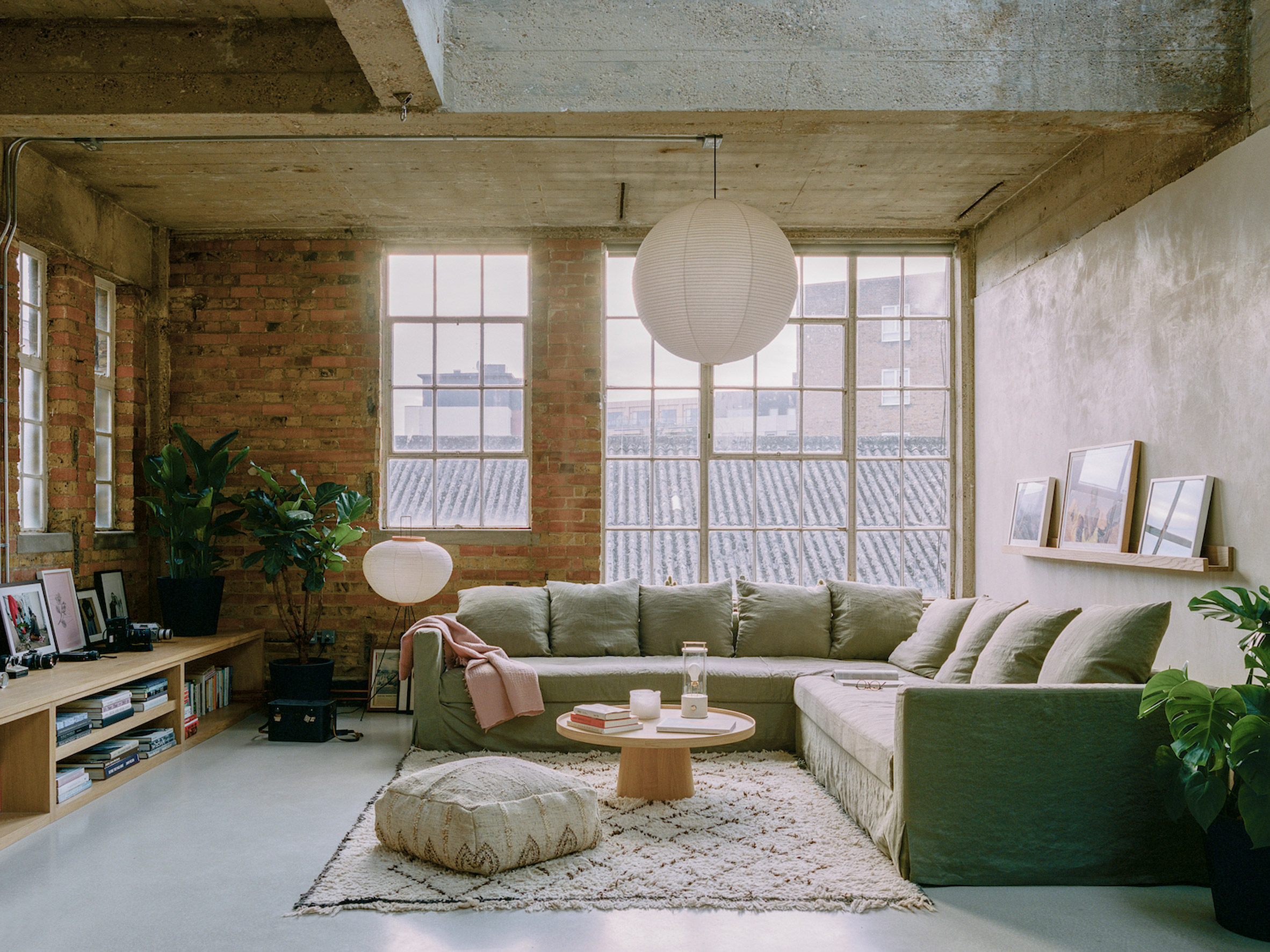 Open plan living room with exposed brick walls and steel windows designed by Studio McW