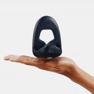 Hand holding up Tanuto 2, a wearable vibrator for erectile dysfunction by MysteryVibe