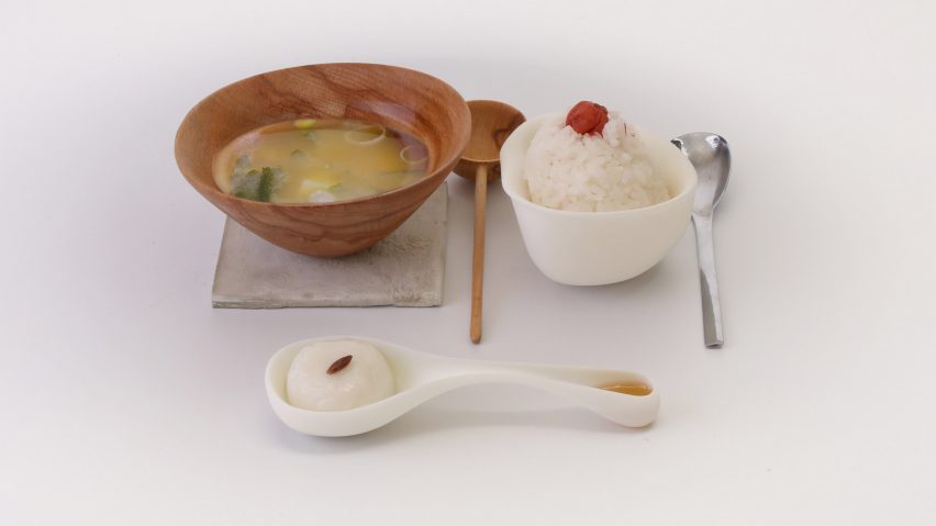 Wooden bowl of miso soup, rice and cutlery laid out on a white table