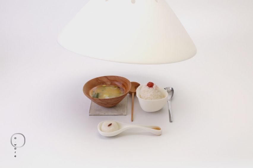Wooden bowl of miso soup, rice and cutlery laid out on a white table