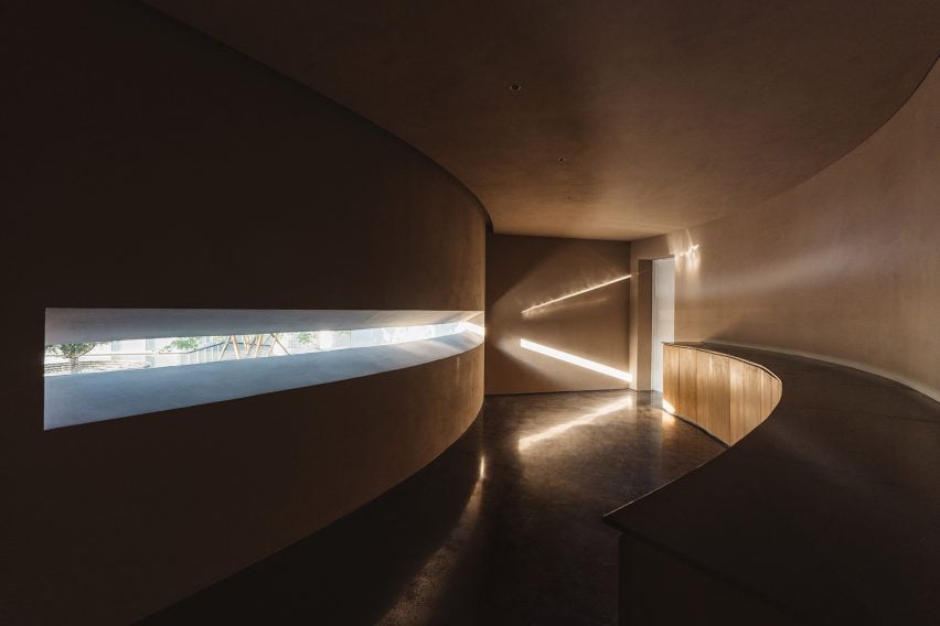 Dark curved corridor with warm moody lighting and slim opening