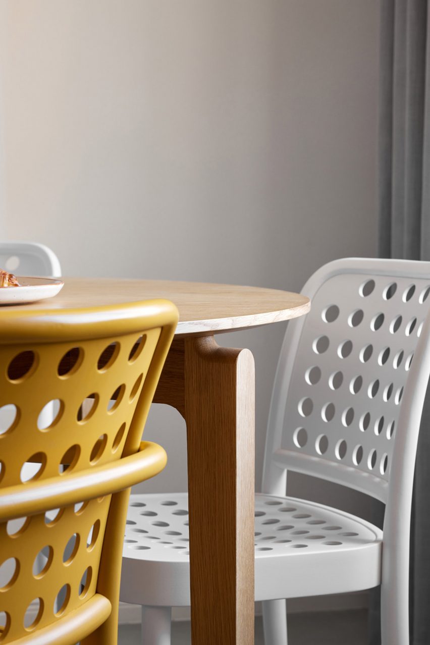 Close-up of a wooden dining table with a white and yellow chairs