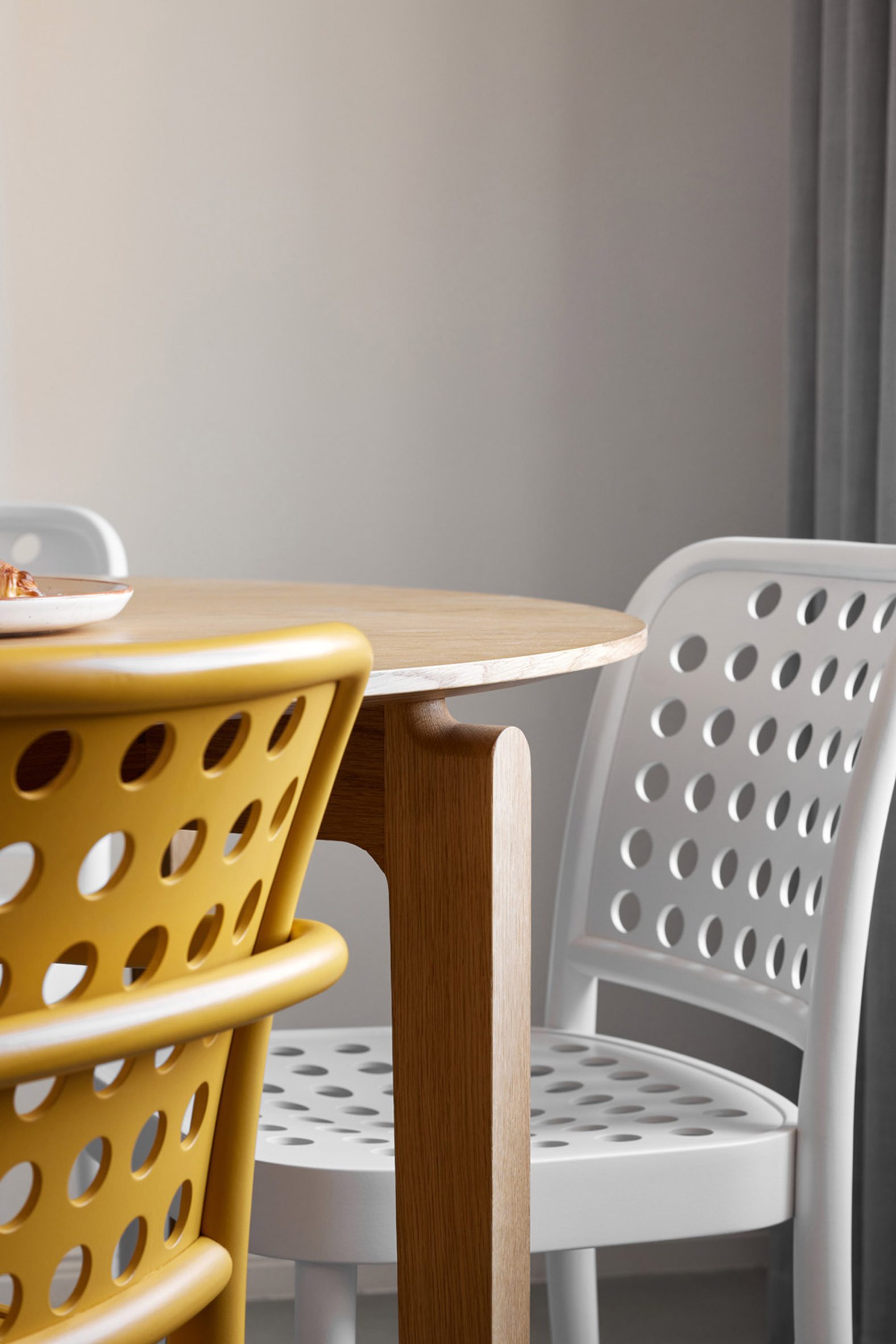 Close-up of a wooden dining table with a white and yellow chairs