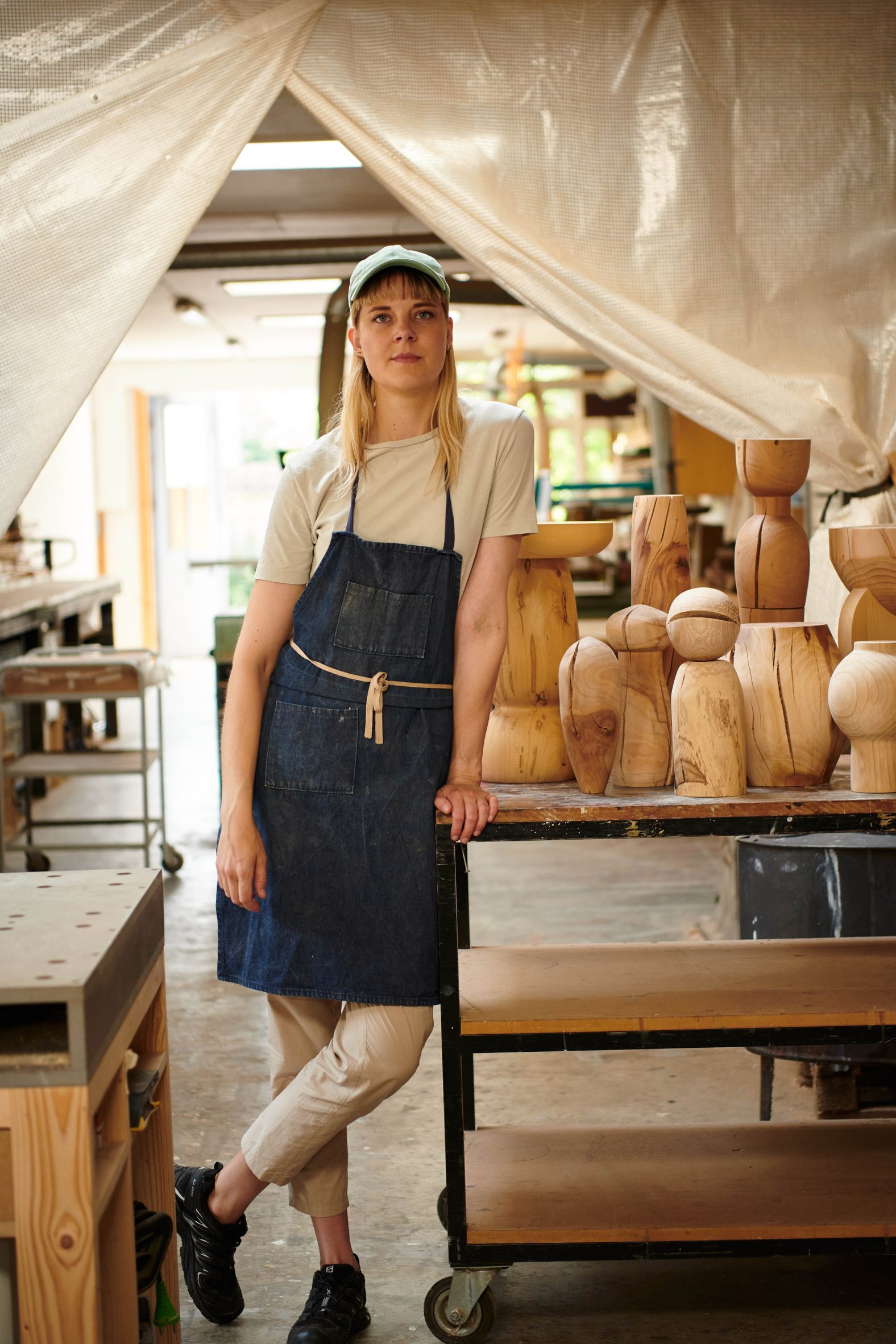 A photograph of a designer next to her wooden objects