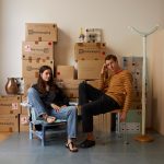 Photo of two people sat in front of cardboard boxes