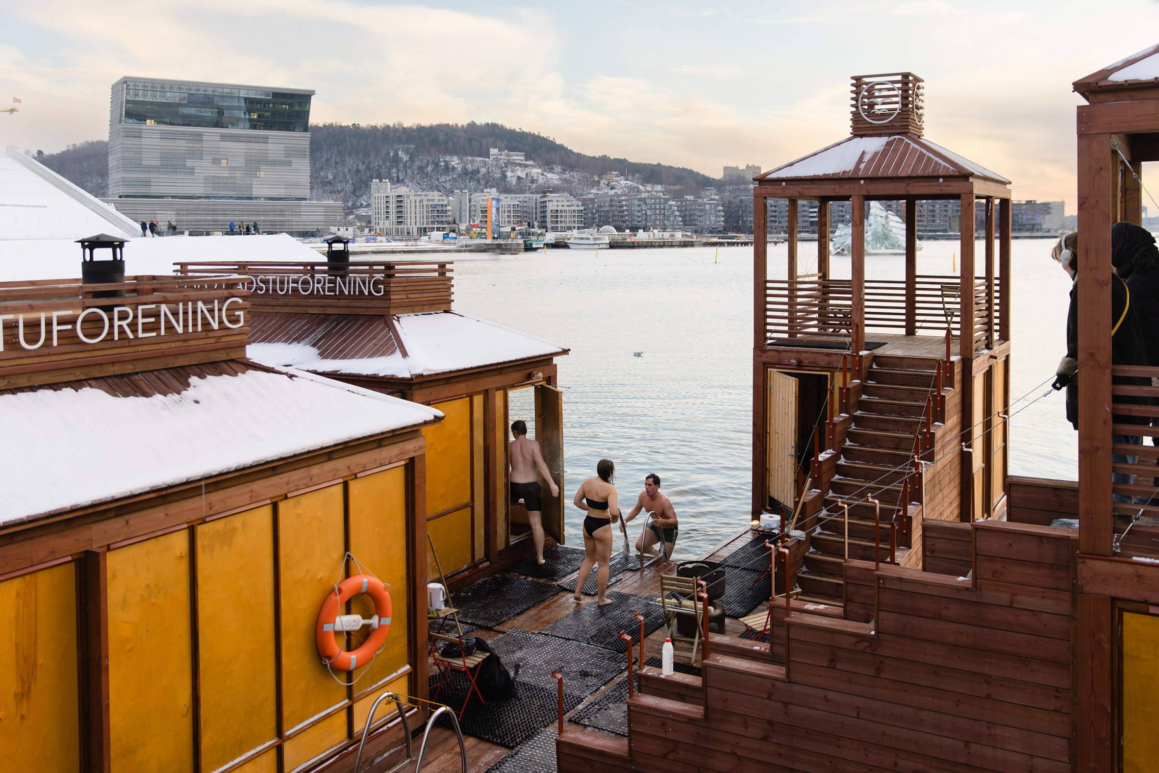 Bright sauna floating on water in Oslo with red staircases and towers