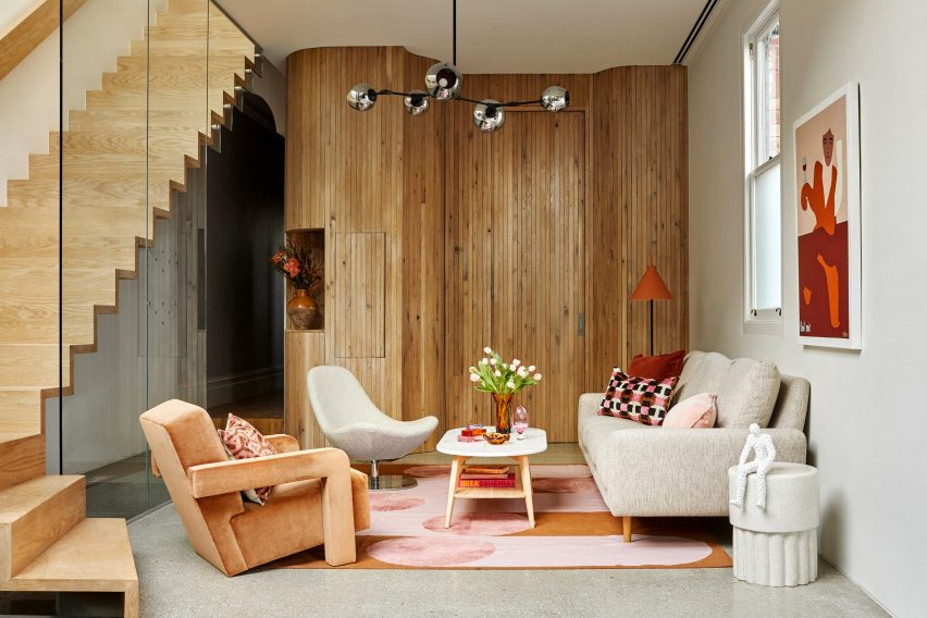 Curved wall lined with wooden slats in the living room with floating staircase