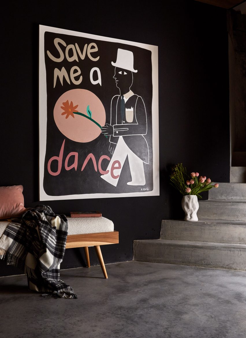 Black chalkboard walls with artwork and grey concrete steps in basement of Melbourne house