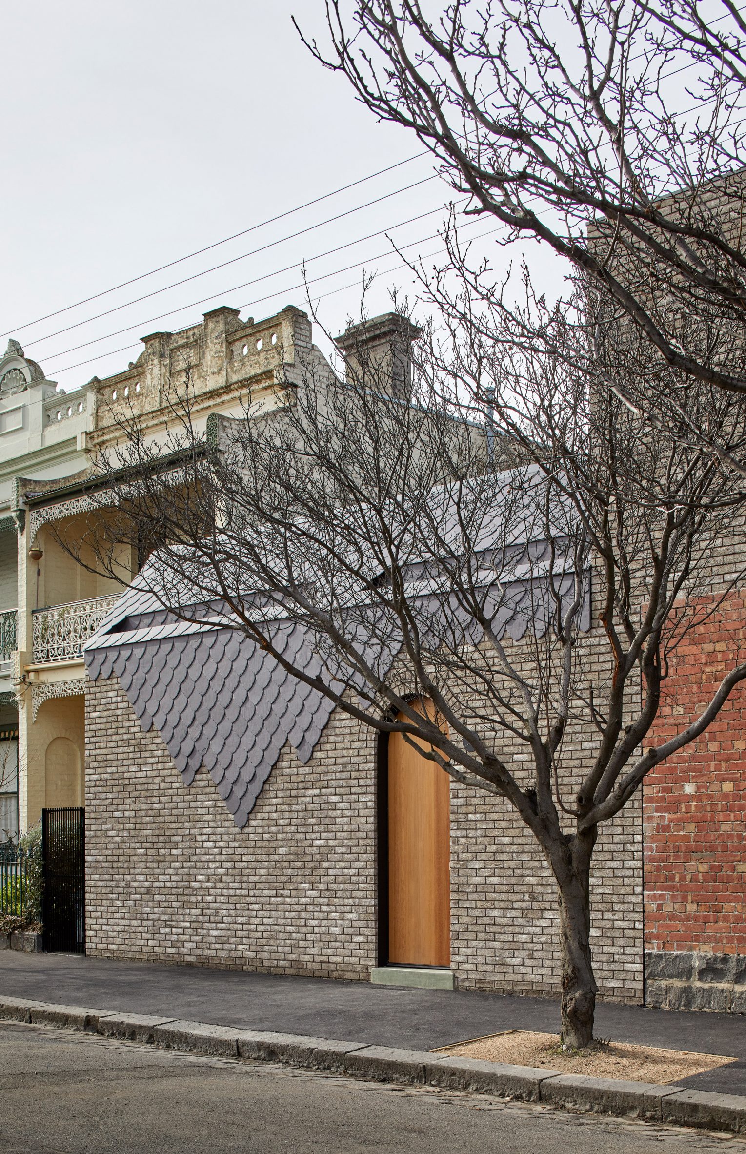 Curved slate tiles on brick building by Angelucci Architects