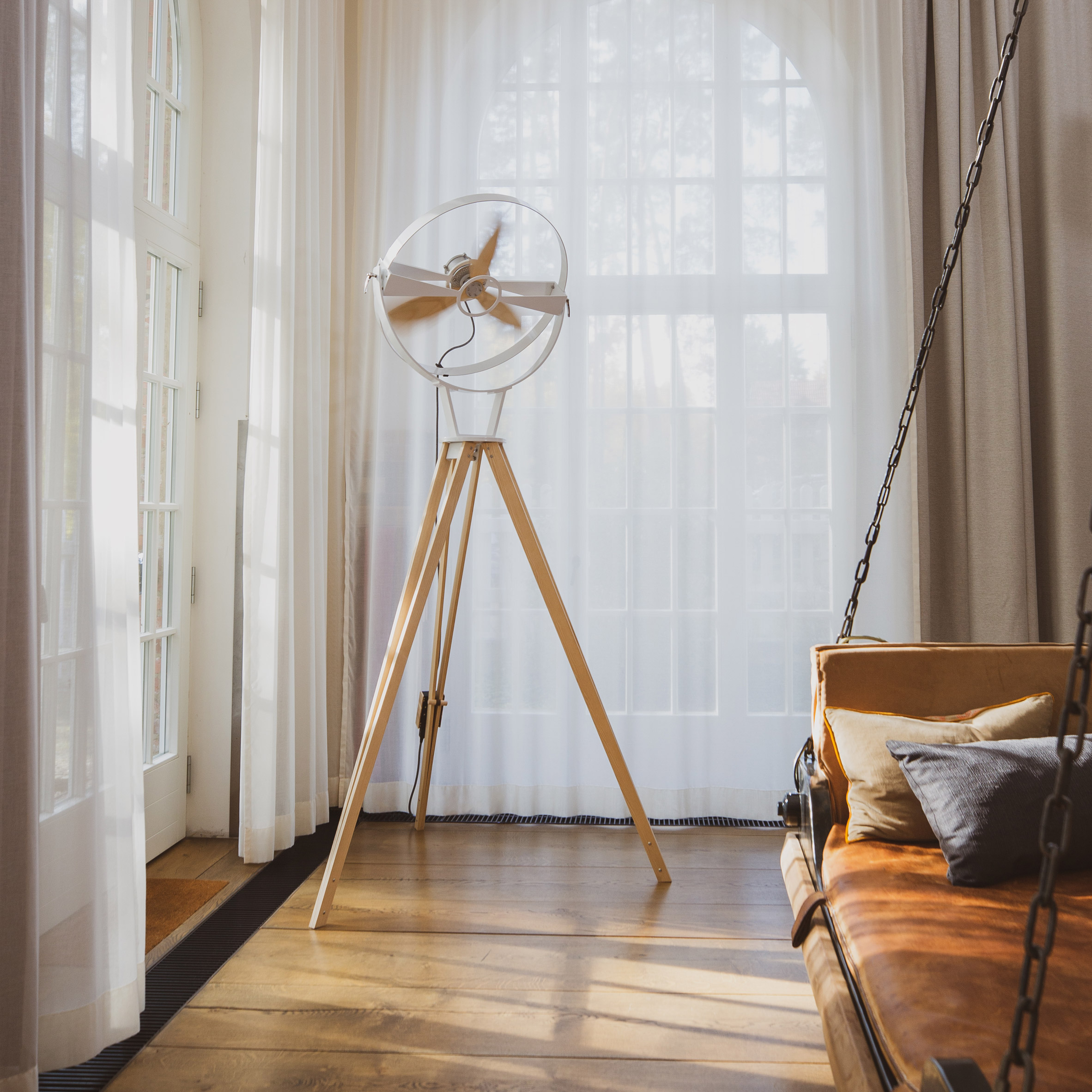 Aura wooden standing fan in the corner of a room with large windows