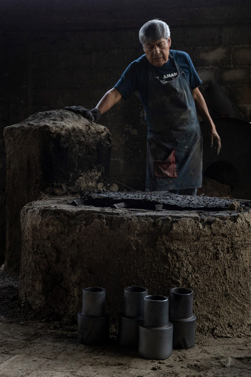 Photograph of a clay craftsmen next to a firing kiln with black clay lamps.