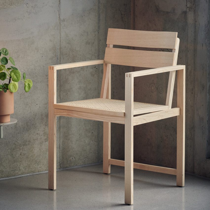 Photograph of wooden chair in concrete room with plant