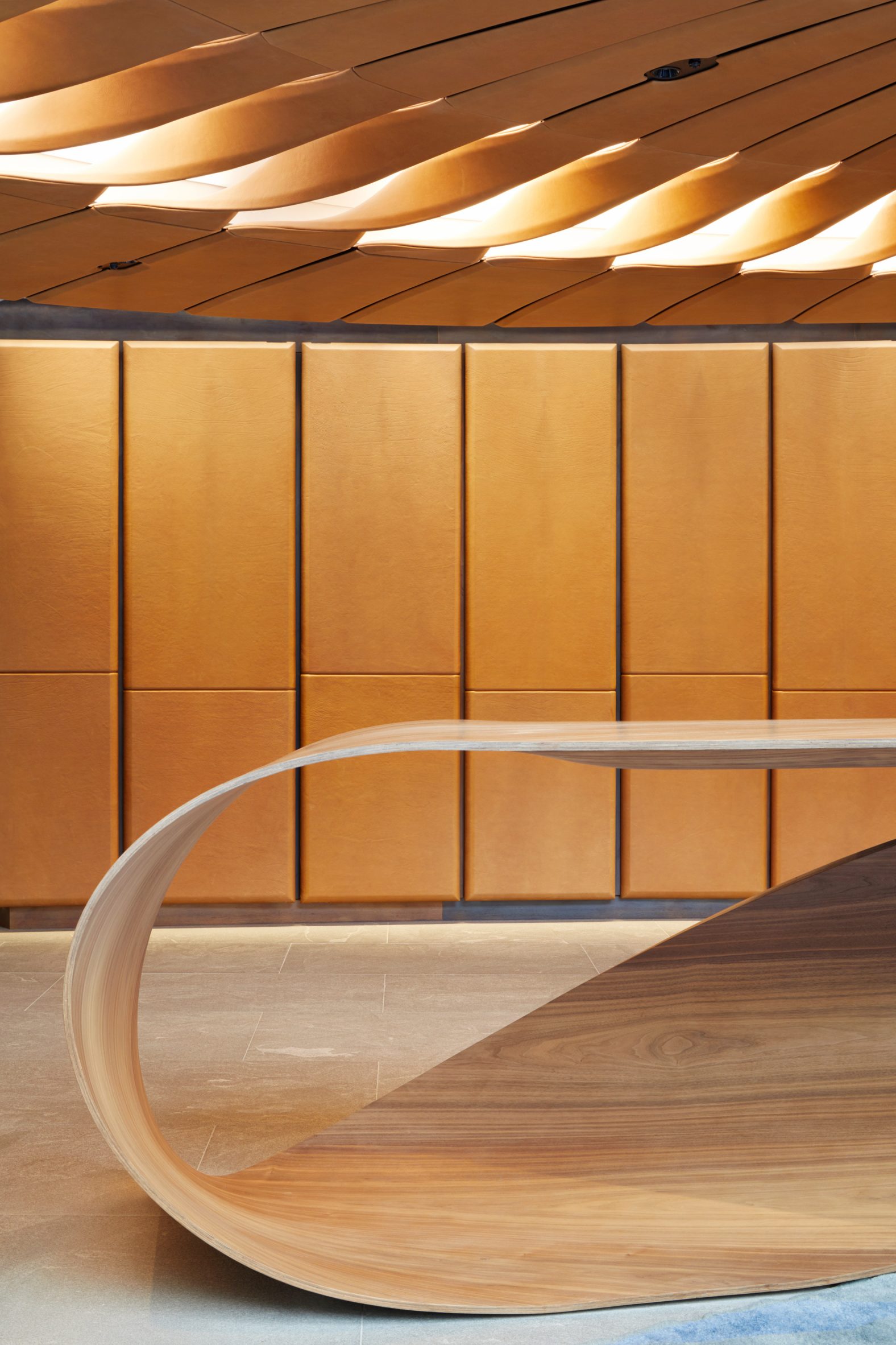 Close-up of bent-wood desk and leather wall panels by Bill Amberg Studio