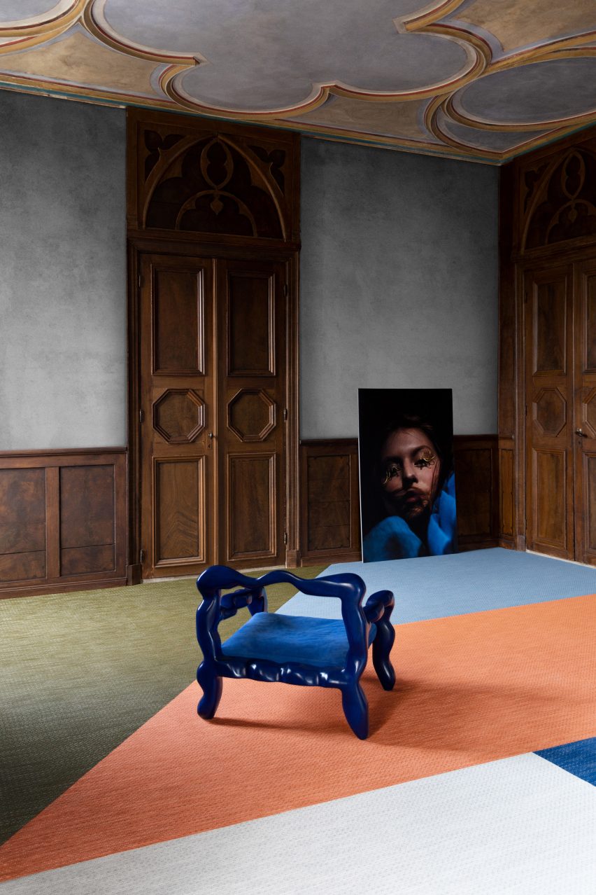 Orange, green and blue angular carpet shapes in a wooden-panelled room with a blue chair