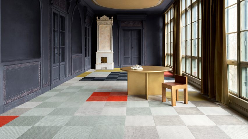 Light blue carpet tiles with some red and dark blue tiles in a wooden-panelled room painted dark blue