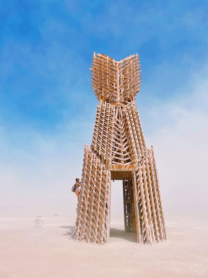 Burning Man wooden sculpture with someone climbing to the side