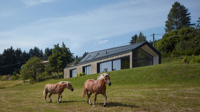 Photograph showing single-level gabled house looking over countryside with horses