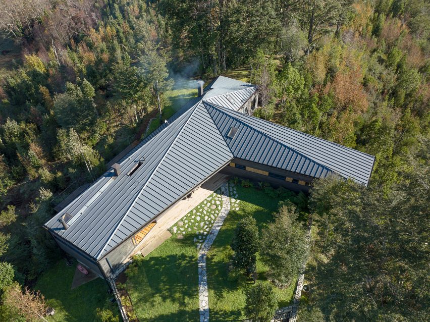 T-shaped house in forest with metal roof and two wings by Hebra Arquitectos