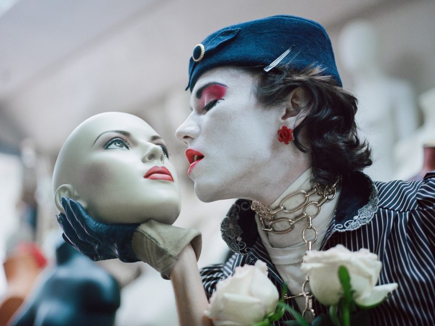 Model in white face paint and blue clothes holding a mannequin head by student at Hong Kong Polytechnic University