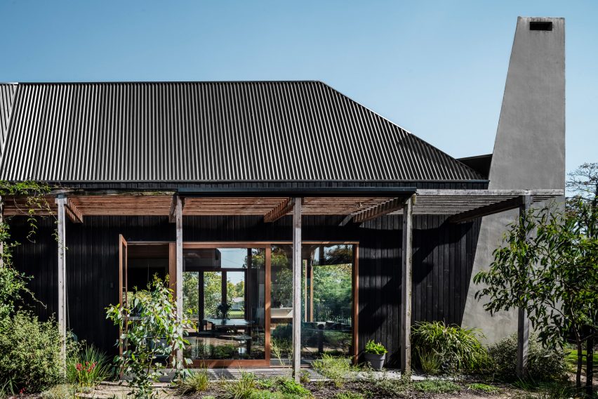 Home with tall black chimney and black roof with verandas surrounding courtyard