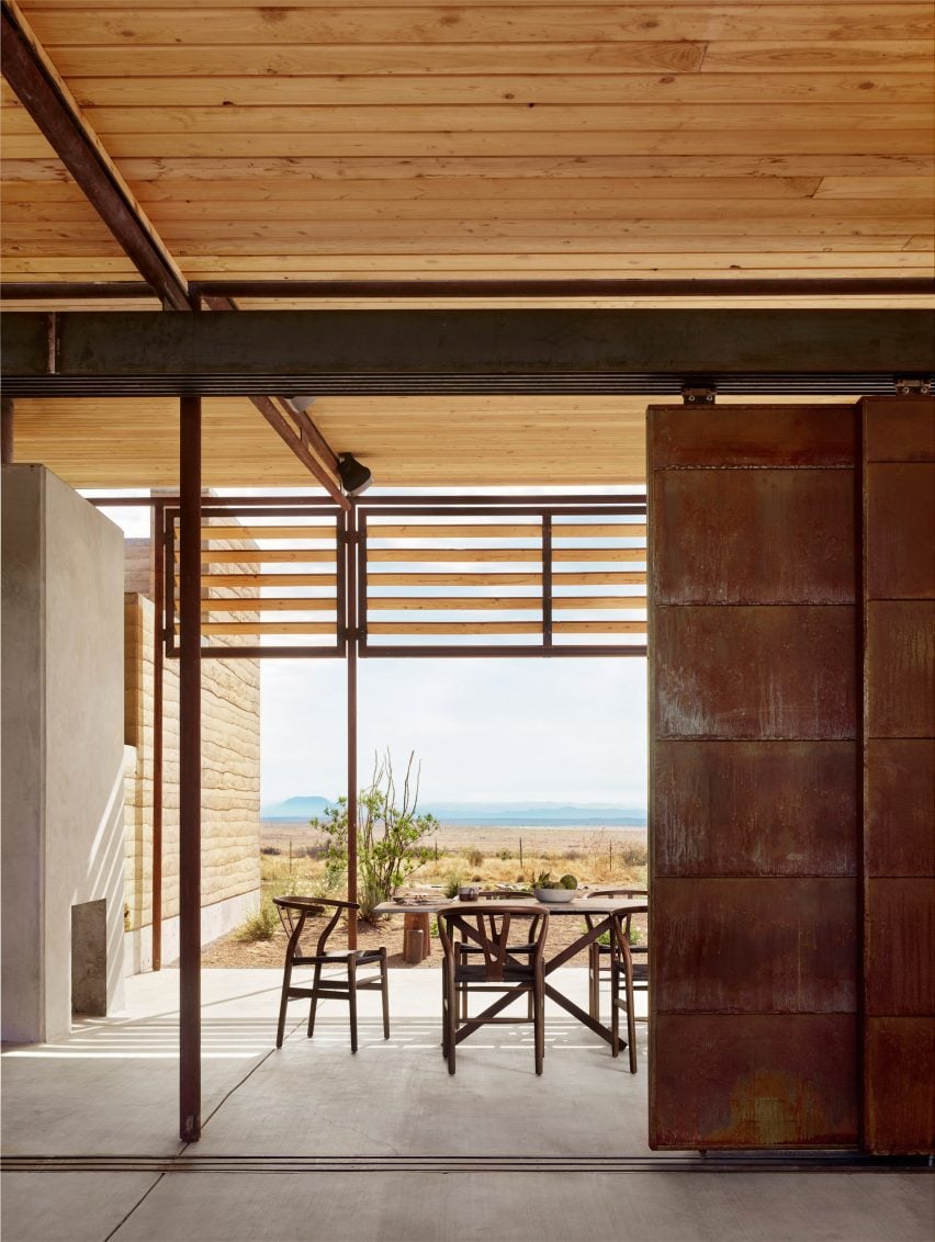 Rusted steel sliding door leading to exterior living space in ranch house by Lake Flato