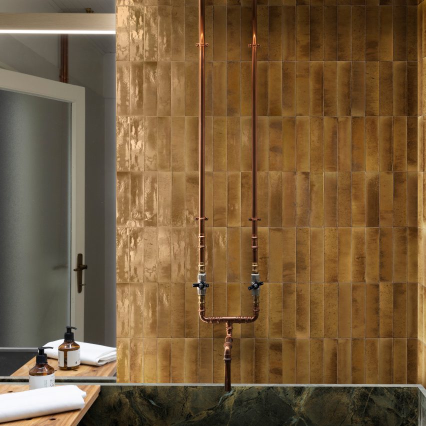 Photograph of bathroom with golden tiles laid vertically behind bath