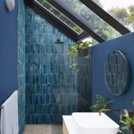Photograph of bathroom with dark blue tiles laid vertically inside shower enclosure