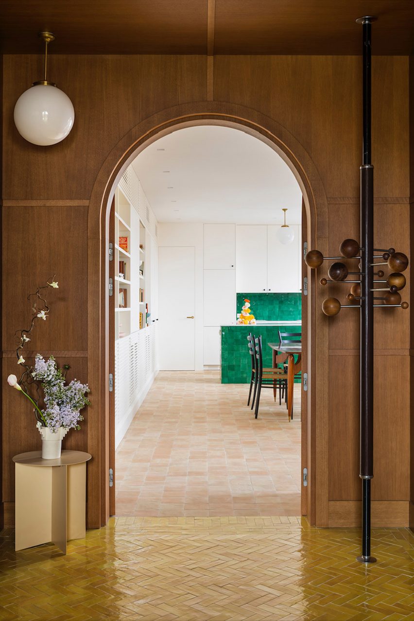 View from the wood-paneled room to the green-tiled kitchen of the Sierra + De La Higuera apartment