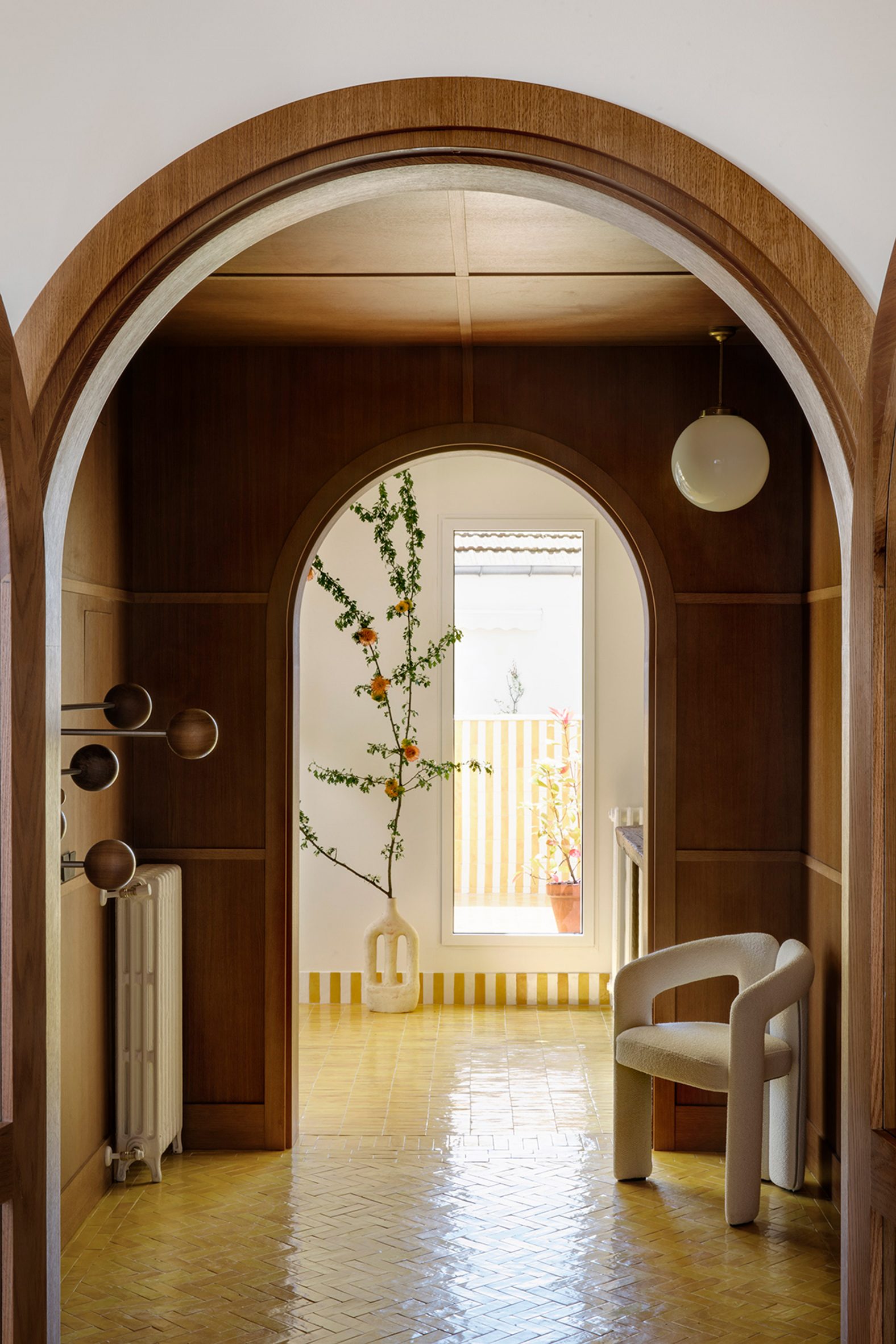 Wood-panelled hallway with white armchair in flat by Sierra + De La Higuera