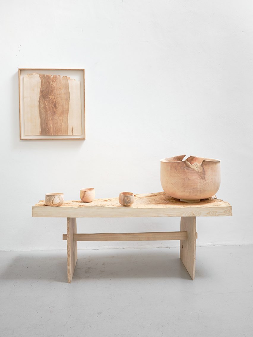 Photograph showing a wall hanging, a bench with bowls on top, all in wood on a white background for SCP's One Tree exhibition at the LDF