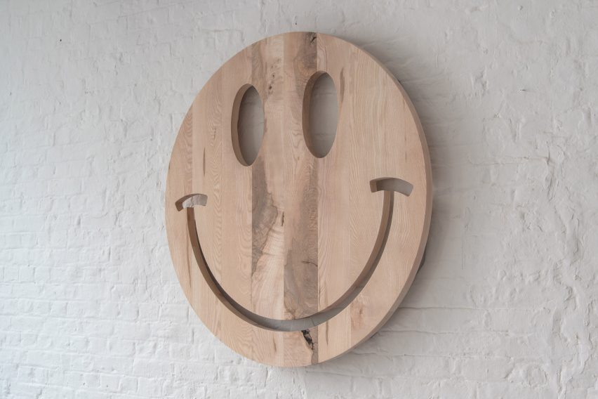 Photograph showing a wooden smiley face against a white painted brick wall for SCP's One Tree exhibition at the LDF