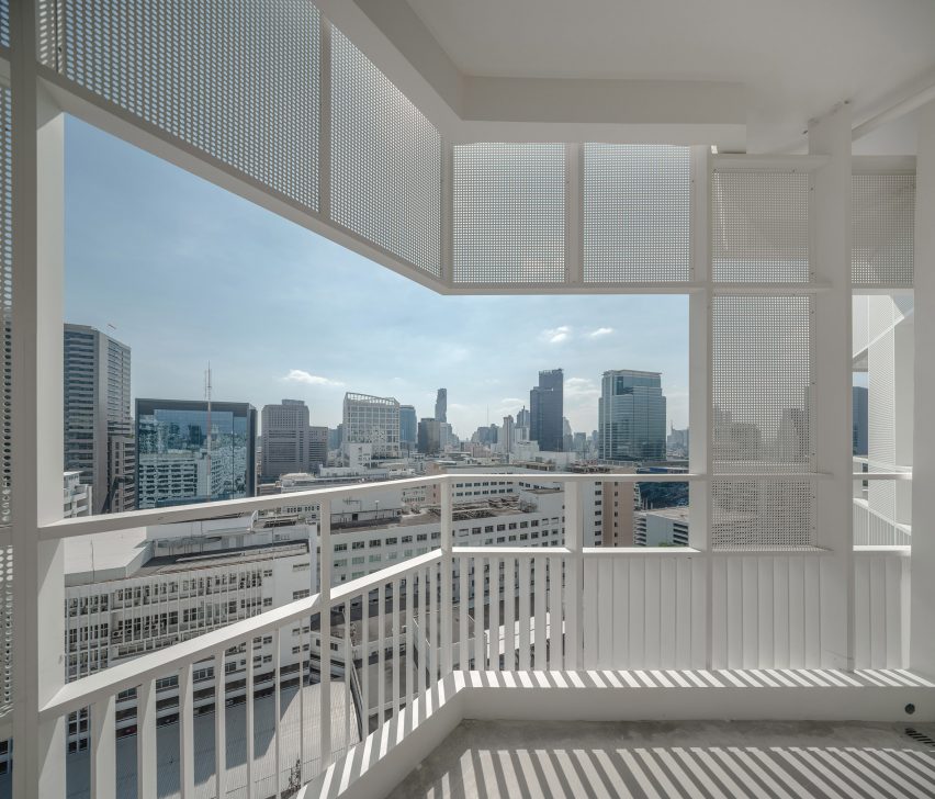 Aluminium railing and perforated aluminium sheets casting shadows across balcony of Bangkok apartment