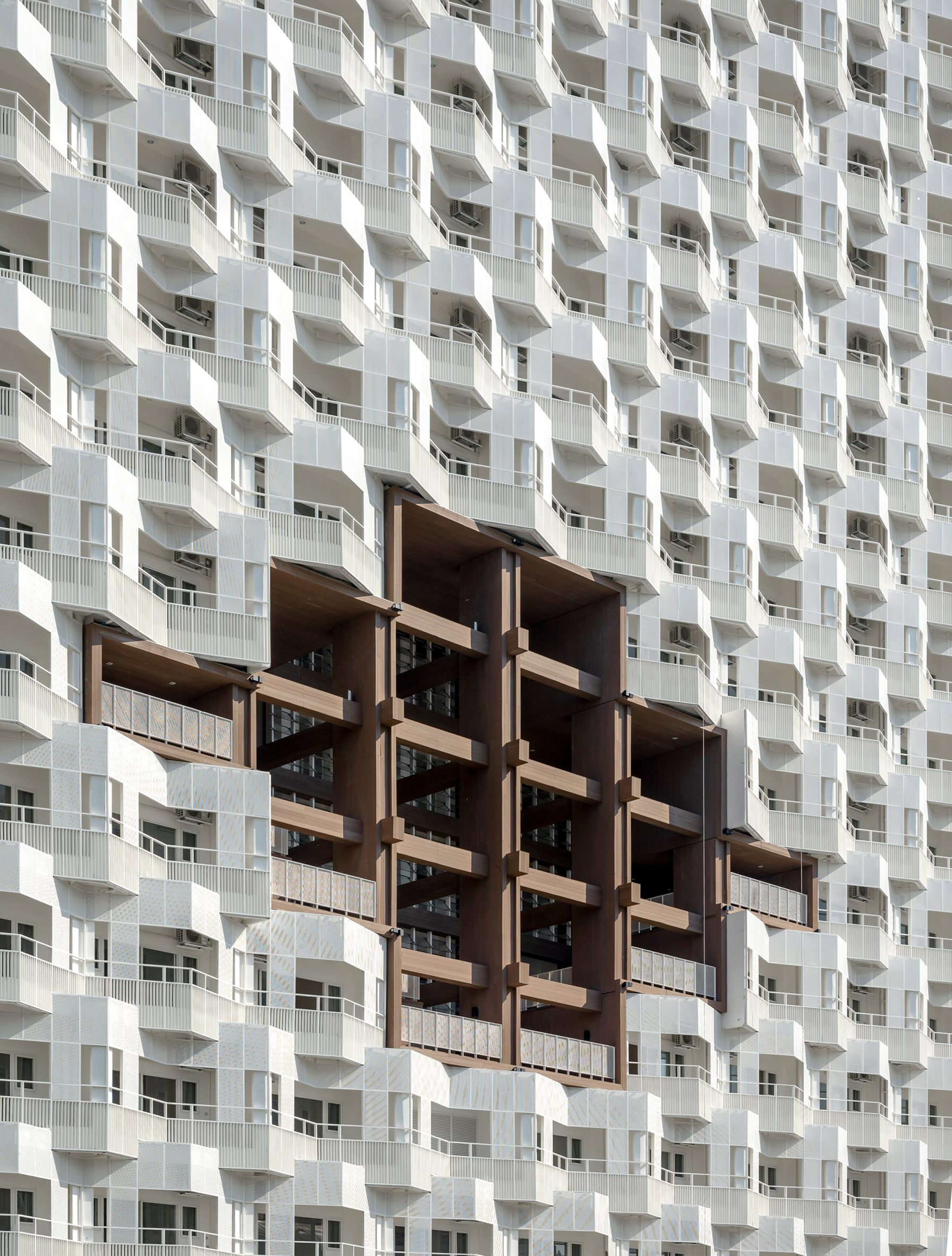 White zigzag facade of building by Plan Architects with brown artificial timber section