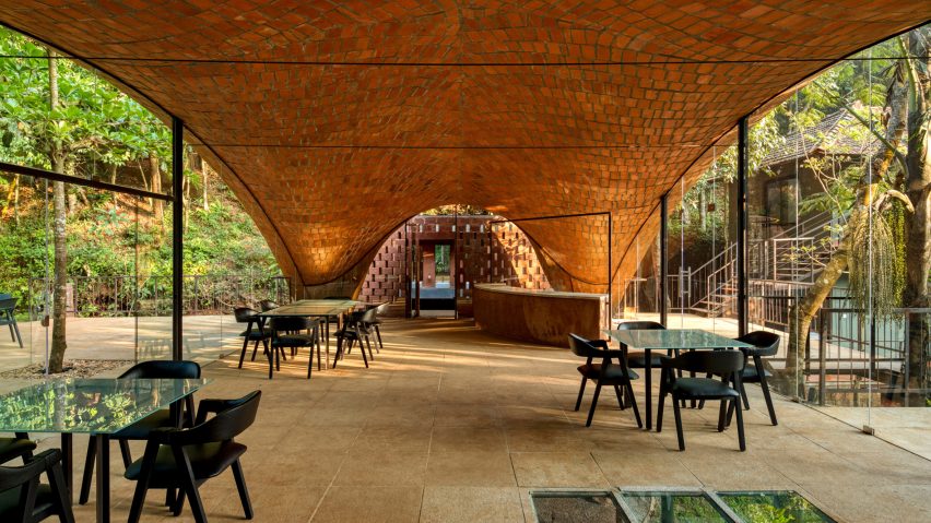 Restaurant seating under a vaulted ceiling with large glass openings