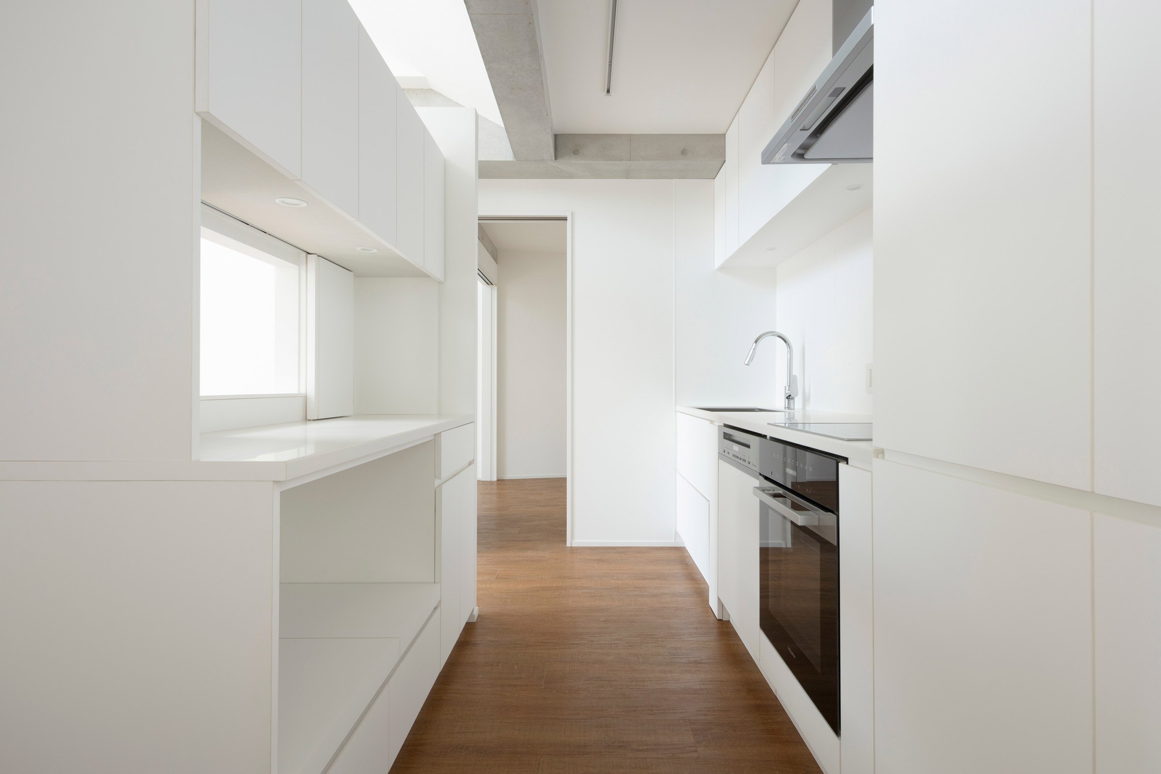 White minimalistic kitchen with brown floor in Tokyo apartment